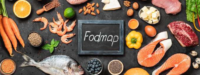 small chalkboard sign with "Fodmap" surrounded by fresh foods, fish, veggies, cheeses etc