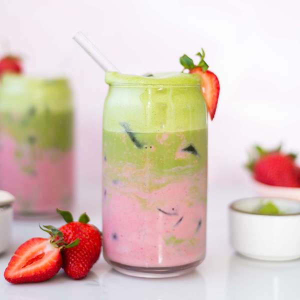 glass of strawberry matcha with strawberries around it