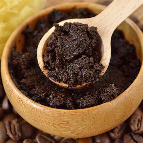 top view of coffee scrub in wooden bowl with small wooden spoon