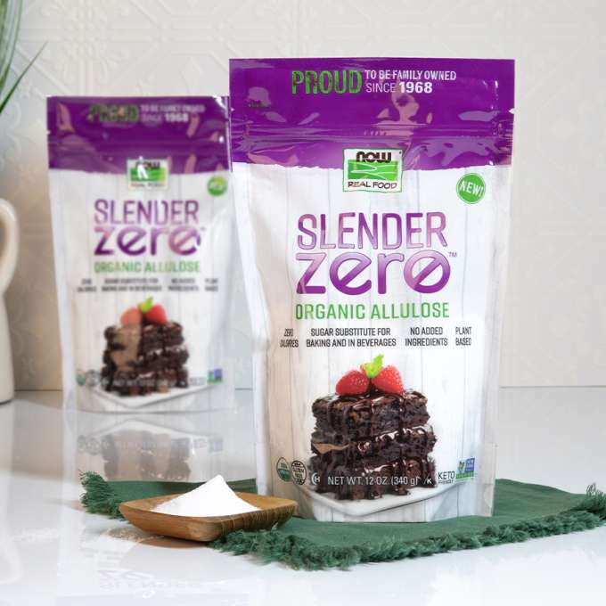 two bags of NOW Allulose on top of a green kitchen towel with a small wooden dish containing Allulose