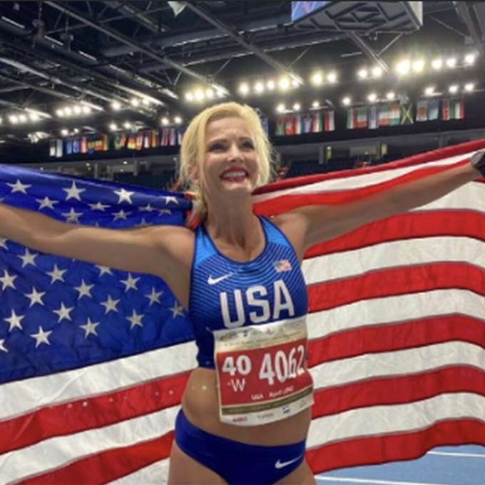 April Lund in team USA uniform holding American flag 