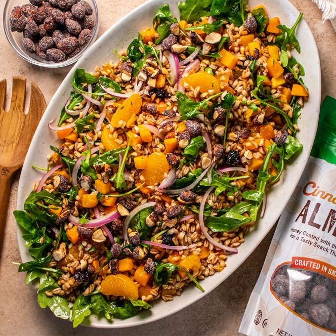 top view of warm ferro salad next to bag of NOW Cinnamon Honey Almonds