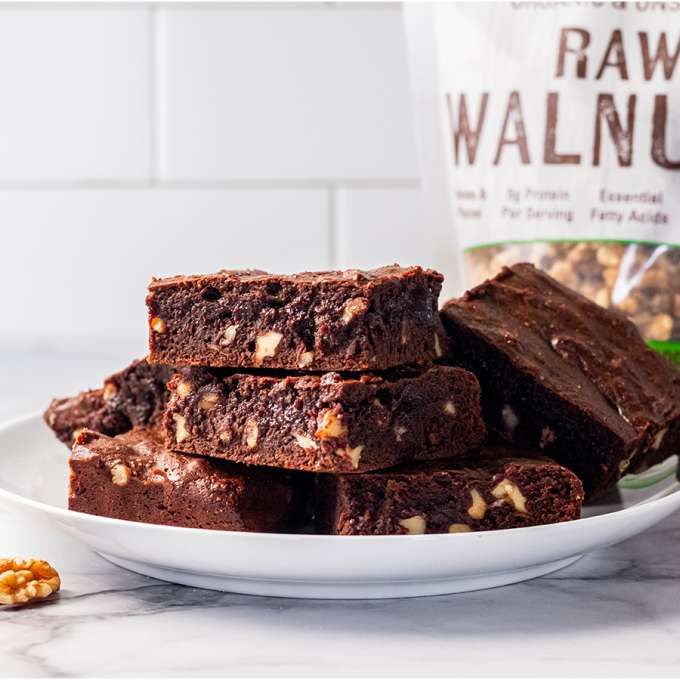 white plate with fudgy walnut brownies on them