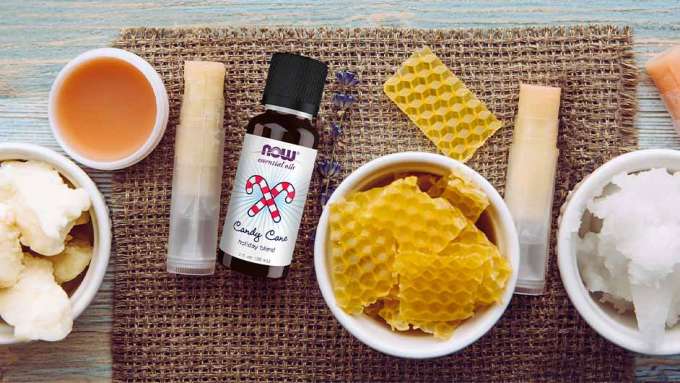 top view of various ingreidents needed to make vandy cane lip balm with the center featuring NOW Candy Cane Essential Oil and a bowl of bees wax