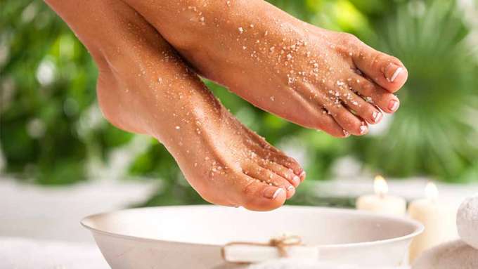 light skinned feet with sugar scrub over a white bowl