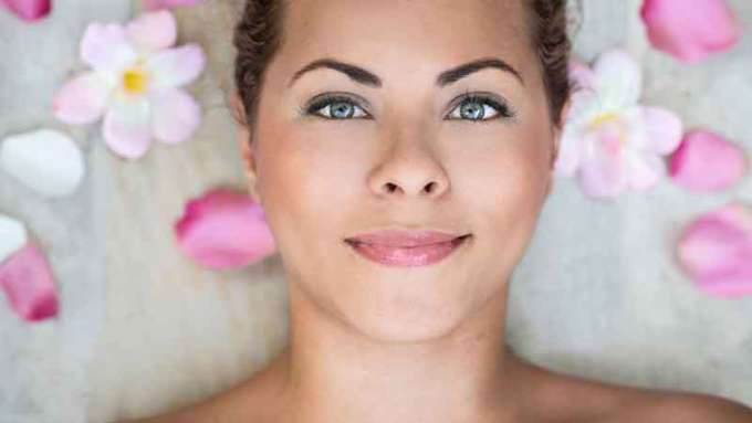 A female-presenting, medium-skin person with green eyes smiles at a camera