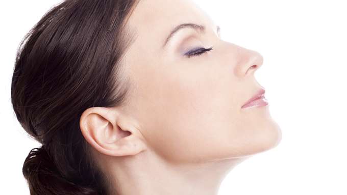 A female-presenting person with light skin and long brown hair has her eyes closed