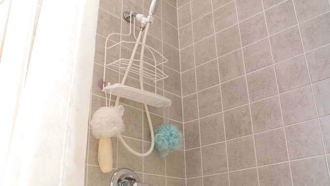The inside of a shower with brown wall tile