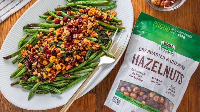 top view of Charred Green Beans with Hazelnut Topping next to a bag of NOW hazelnuts