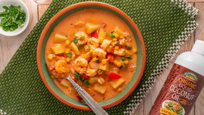 top view of Creamy Coconut Shrimp and Vegetable Chowder next to a bottle of Ellendales Coconut Cooking Oil