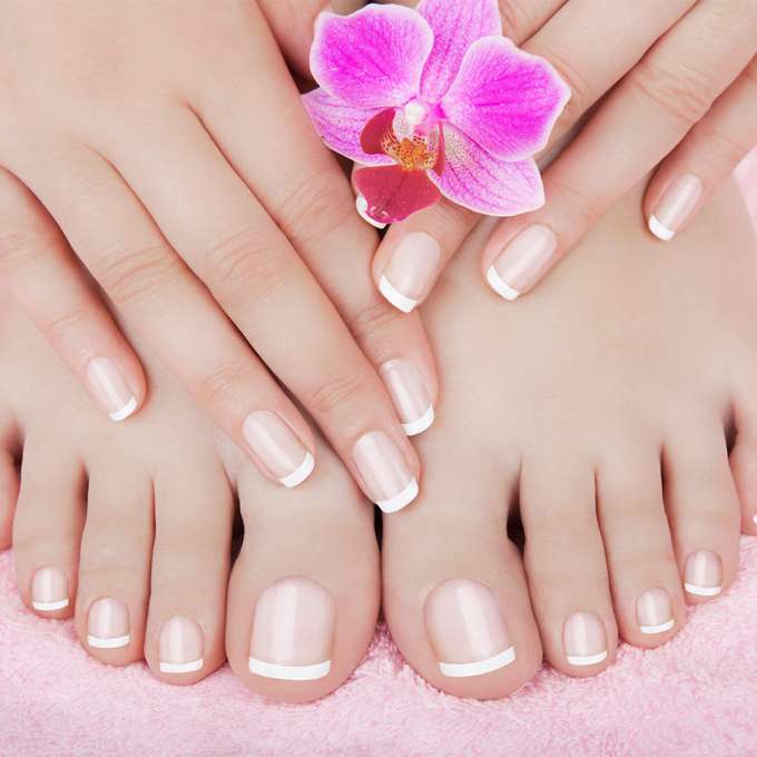 A person with light skin offscreen places their feet and hands on a soft pink towel for the camera.