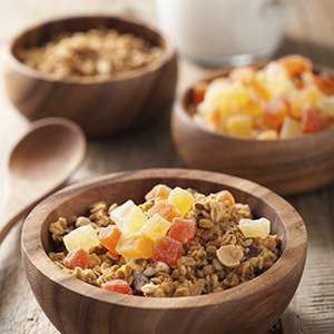 A small wooden bowl on a wooden table is filled with Bahama Mama Healthy Tropical Oatmeal