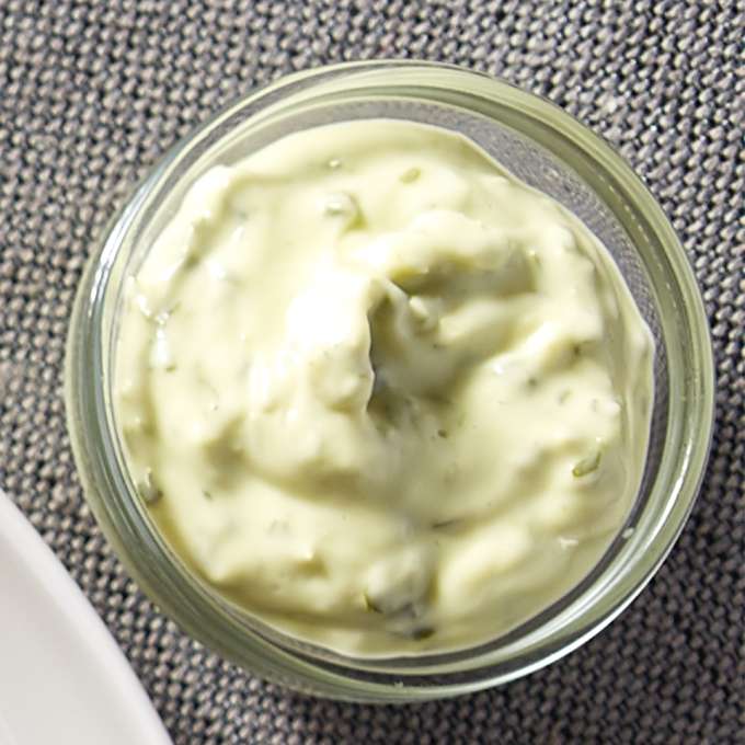 A small dipping bowl filled with Cilantro Sesame Aioli placed on a grey placemat.