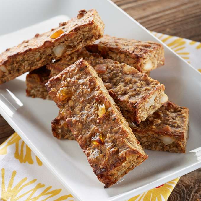 A white plate on a floral napkin holds two Coconut Flax Crunch Bars