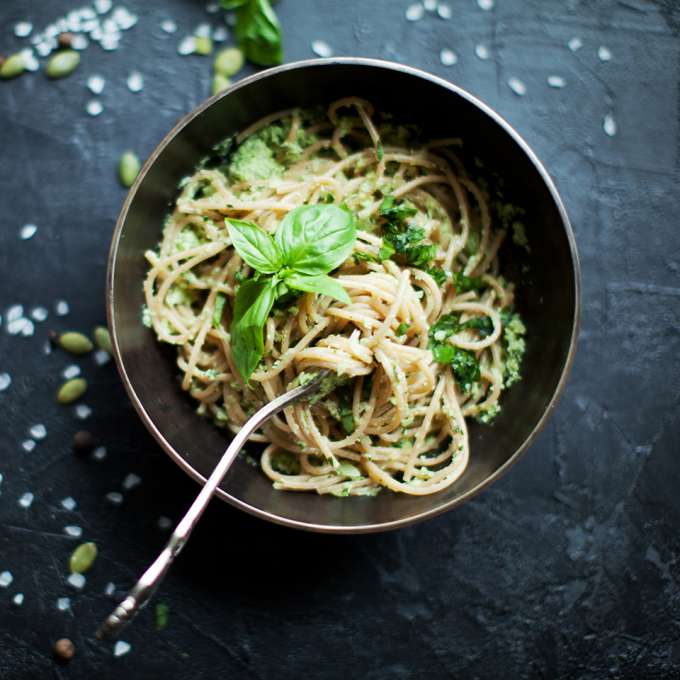 dinner bowl with pasta garnished with basil with a fork