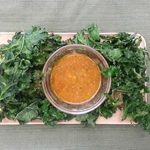 A wooden plate holding Lime Kale Chips