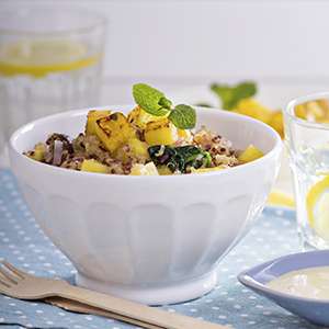 A white ceramic bowl on a blue and white placemat holds a serving of Winter Harvest Quinoa Salad