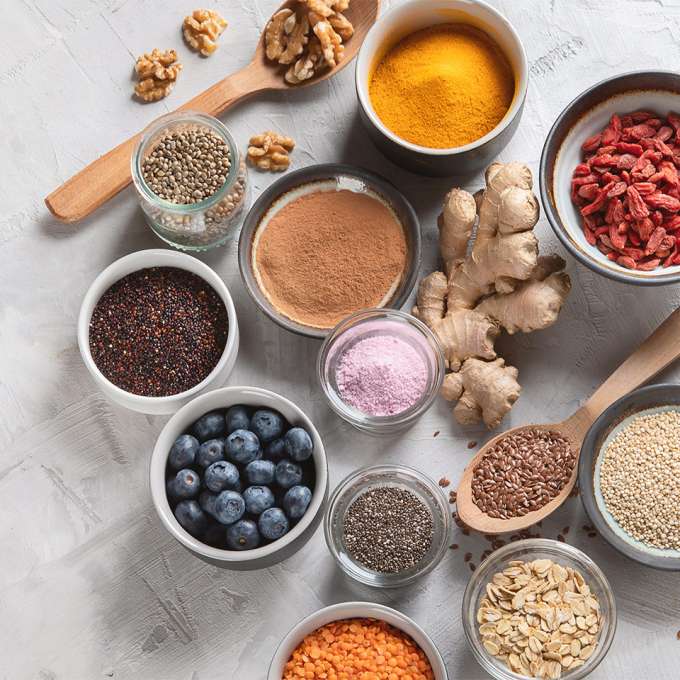 several small bowls filled with berries, seeds and powders