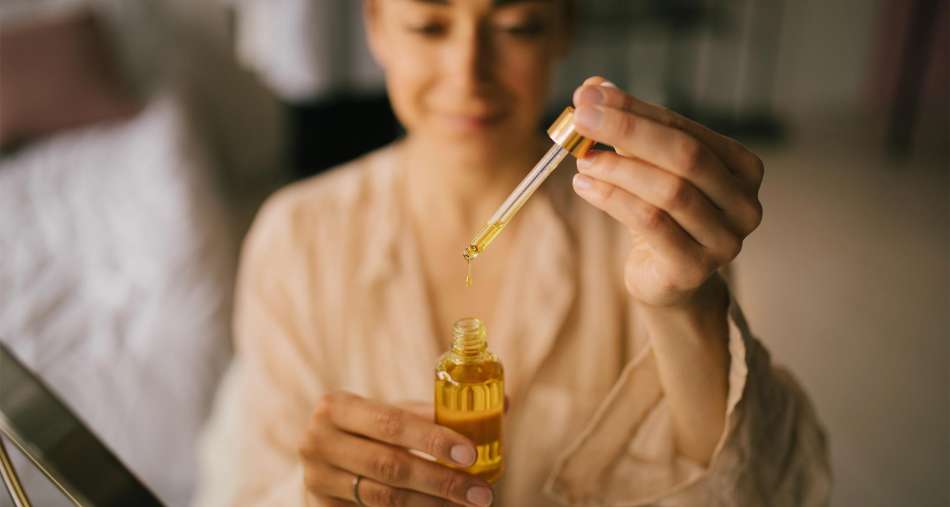 light-skinned, female presenting person adding essential oils to carrier oil