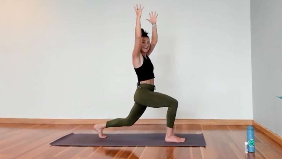 Nicci Randall doing a lung on yoga mat with her hands in the air