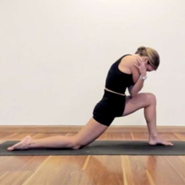 light skin female presenting person doing a yoga lunge in black shorts and a black tank top