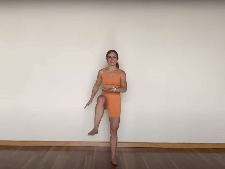 light skin female presenting person wearing all orange mid jump while jumping side to side