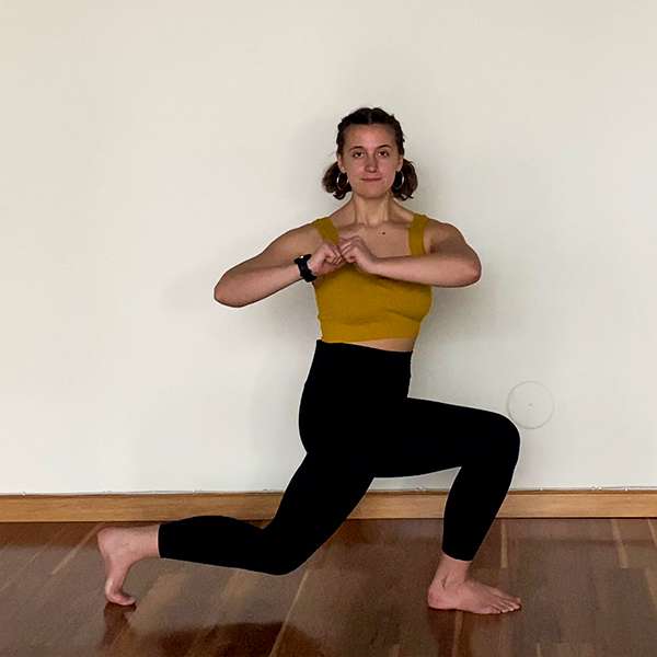 female presenting person in black pants and yellow top doing a lunge 