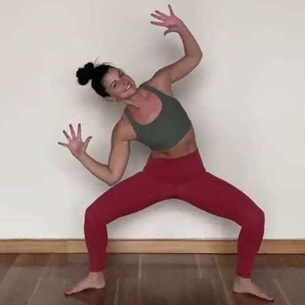 light skin female presenting person wearing red pants and a green sports bra doing a squat