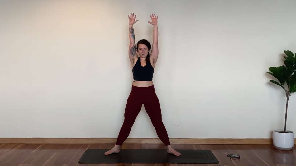 female presenting person in work out clothes standing with their arms in the air