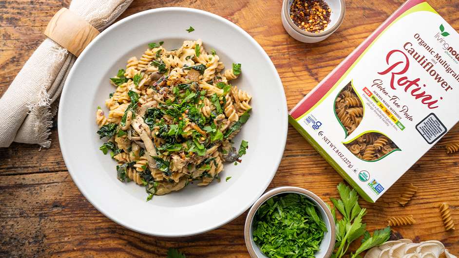 top view of bowl of creamy mushroom kale rotini next to box of NOW rotini