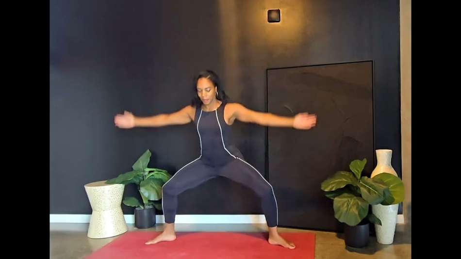 Georgette Dunn standing on a red yoga mat in a mostly black room wearing all black yoga clothes