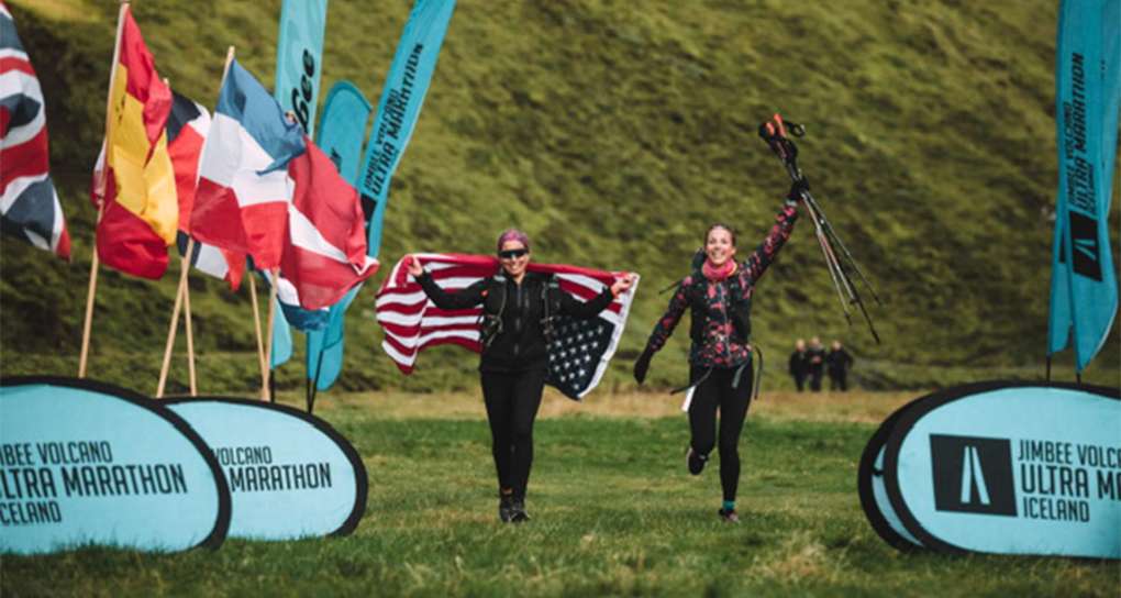 Rachel Belmont crossing finish line with American flag draped over her shoulder